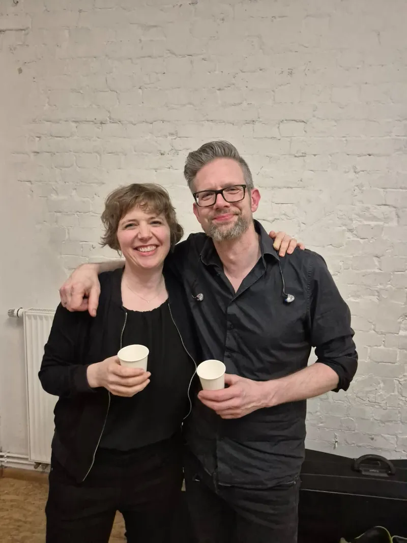 Zwei Mitwirkende mit Kaffeebechern nach der Präsentation